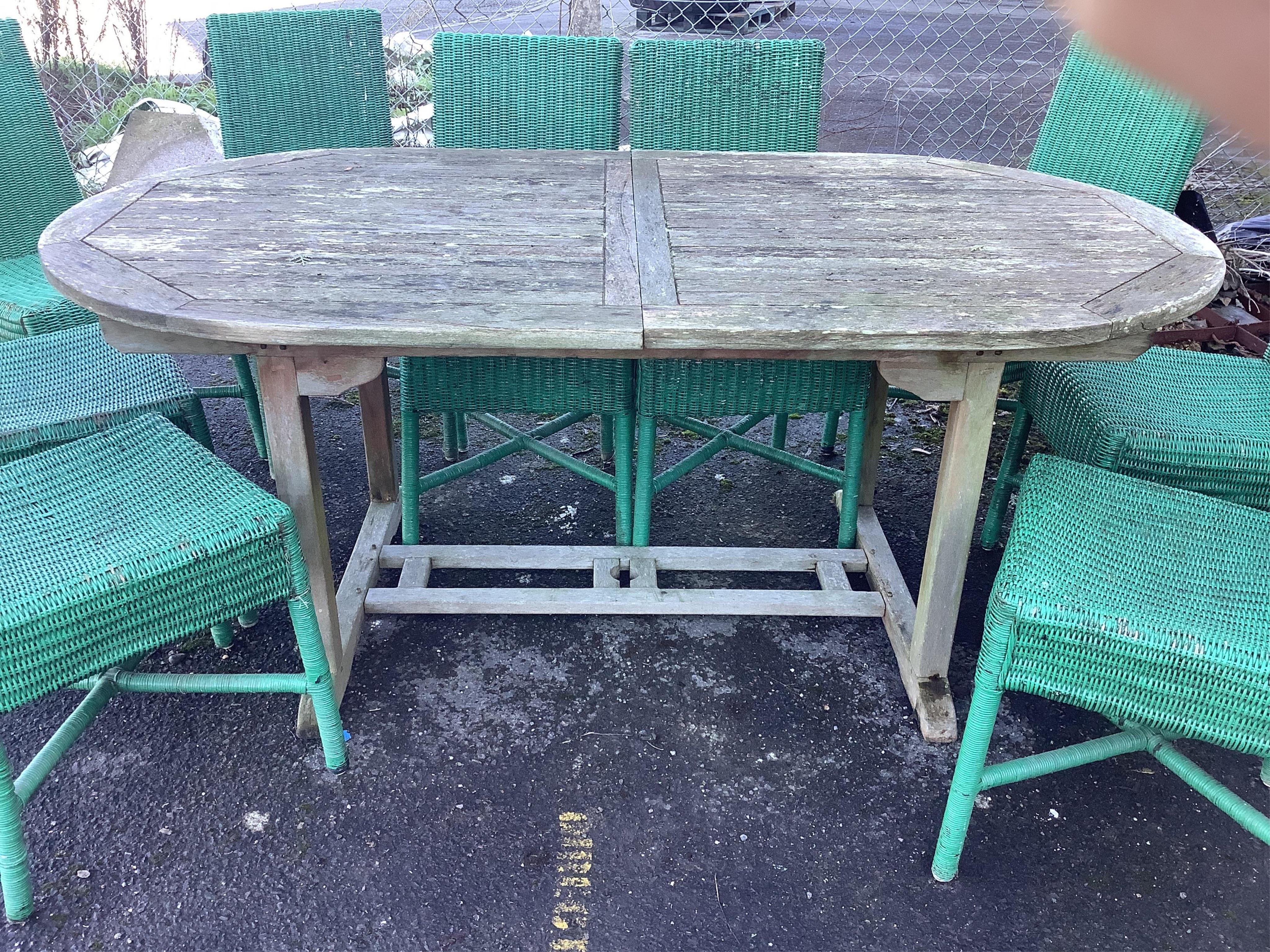 A weathered teak garden table, width 180cm, depth 99cm, height 75cm and eleven Habitat wicker chairs. Condition - poor